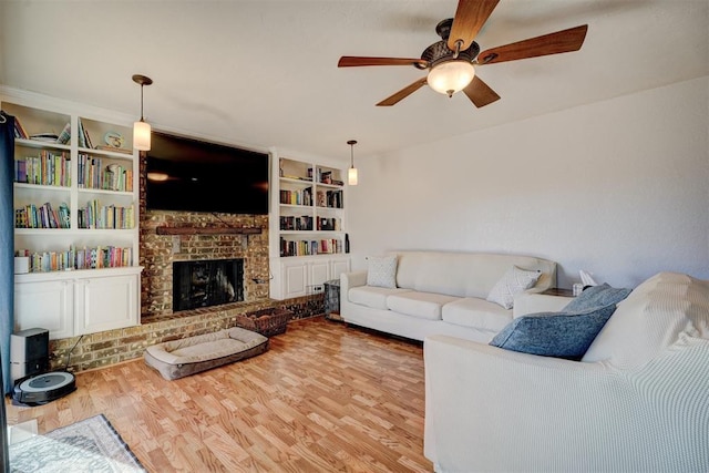 living room with hardwood / wood-style flooring, ceiling fan, a fireplace, and built in shelves