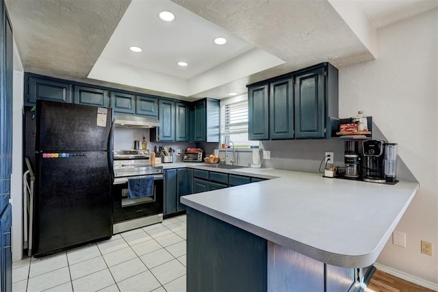 kitchen with sink, black refrigerator, a tray ceiling, stainless steel electric range oven, and kitchen peninsula