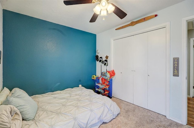 carpeted bedroom with ceiling fan and a closet