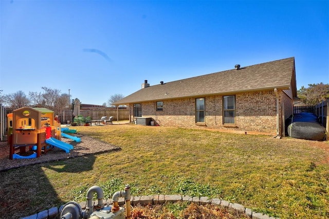 rear view of property featuring a yard and a playground