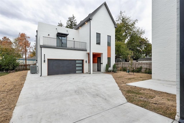 view of front of house with central AC unit, a garage, and a balcony