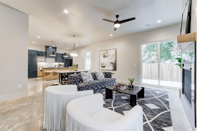 living room featuring ceiling fan with notable chandelier and plenty of natural light