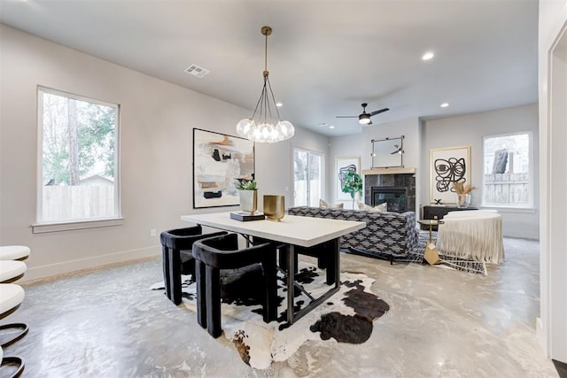 dining room featuring ceiling fan with notable chandelier and a tile fireplace