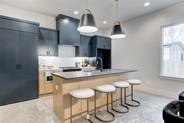 kitchen featuring wall chimney exhaust hood, decorative light fixtures, sink, and a breakfast bar area