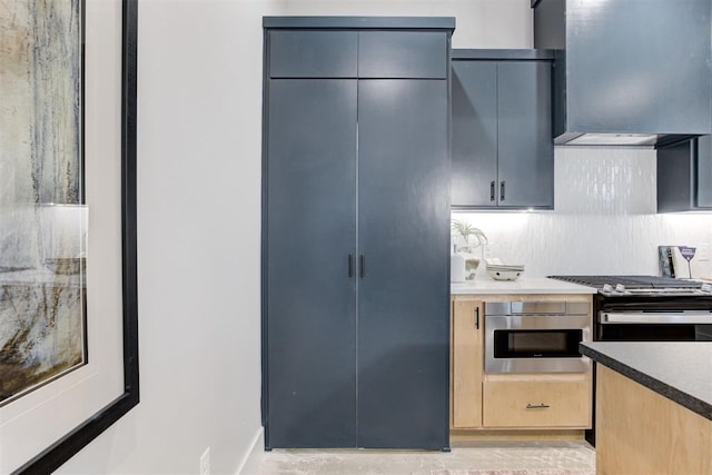 kitchen with appliances with stainless steel finishes, decorative backsplash, light brown cabinetry, and wall chimney exhaust hood