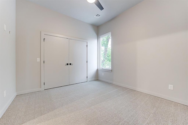 unfurnished bedroom with ceiling fan, light colored carpet, and a closet