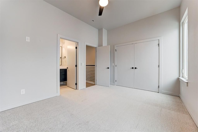 unfurnished bedroom featuring ceiling fan, light carpet, ensuite bath, and a closet