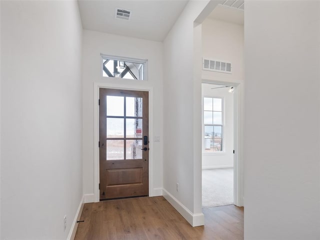 entryway with a high ceiling, visible vents, baseboards, and wood finished floors