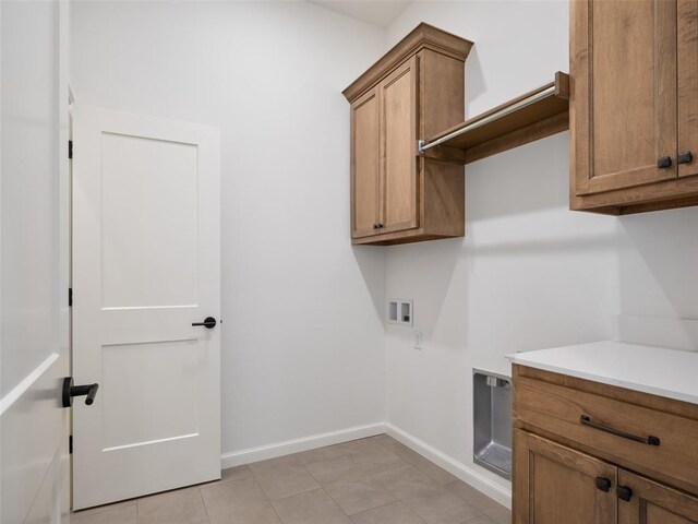 washroom with hookup for a washing machine, cabinet space, baseboards, and light tile patterned floors