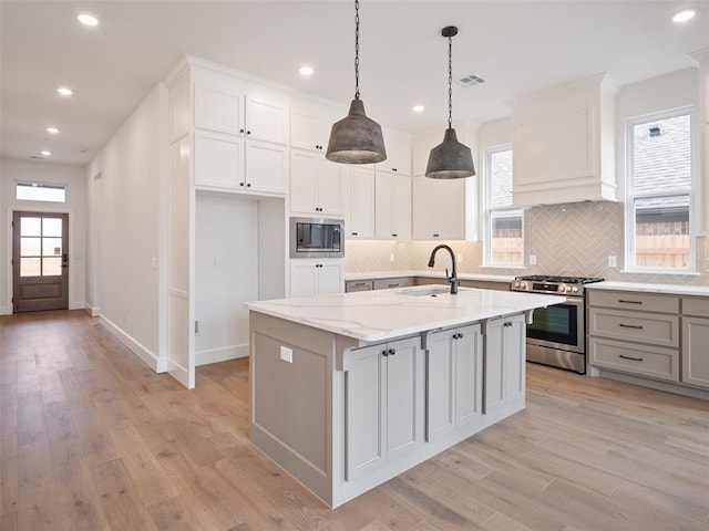 kitchen featuring a sink, visible vents, light wood-type flooring, built in microwave, and gas range