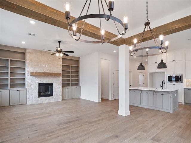 kitchen featuring a sink, stainless steel microwave, open floor plan, and beamed ceiling