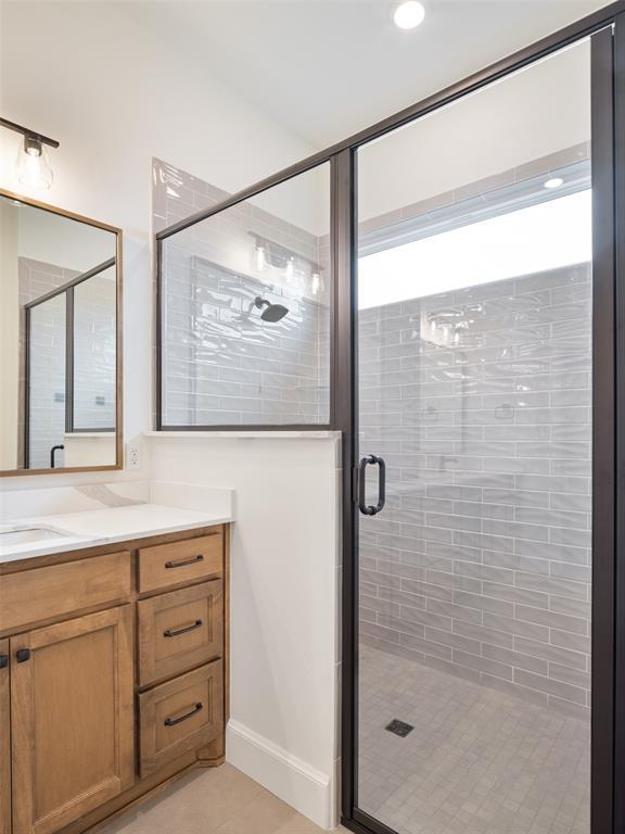 bathroom with a stall shower, tile patterned flooring, and vanity