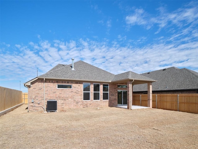 rear view of property with brick siding, a patio, a shingled roof, cooling unit, and a fenced backyard