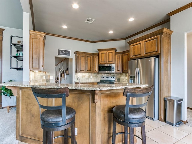 kitchen featuring a breakfast bar, kitchen peninsula, stainless steel appliances, light stone countertops, and backsplash