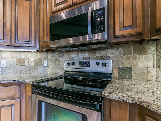 kitchen featuring light stone countertops, backsplash, and stainless steel appliances