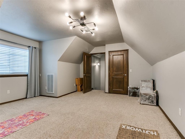 bonus room with lofted ceiling, light colored carpet, and a textured ceiling