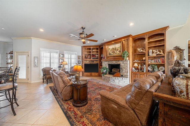 living room with light tile patterned floors, ceiling fan, a fireplace, ornamental molding, and built in shelves