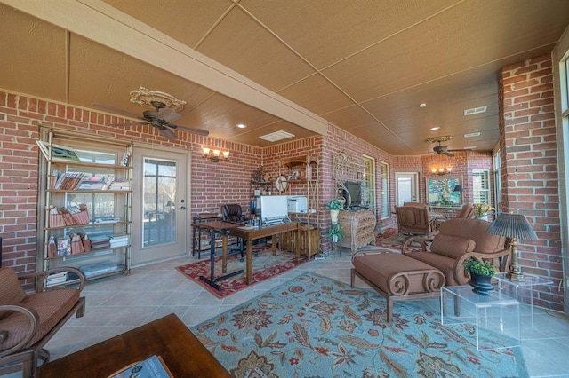 tiled living room featuring ceiling fan and brick wall