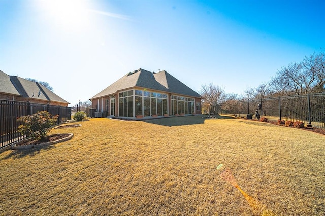 back of house featuring a sunroom and a lawn