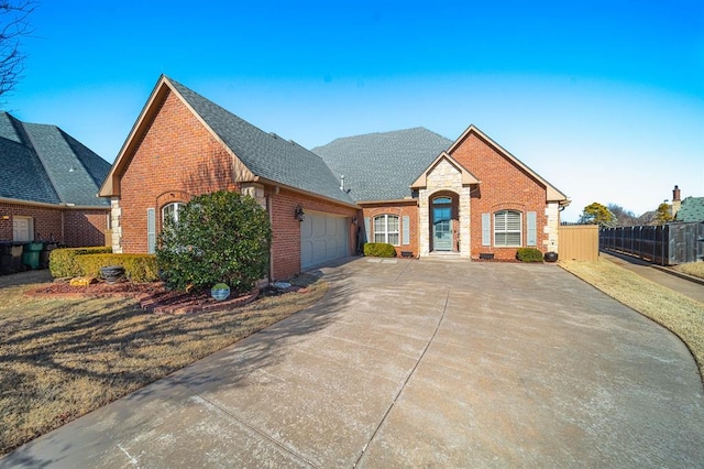 view of front of home featuring brick siding, a shingled roof, concrete driveway, fence, and a garage