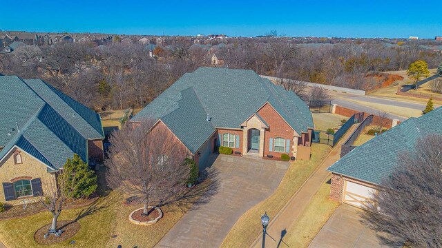 view of front of home with driveway, stone siding, a shingled roof, and fence