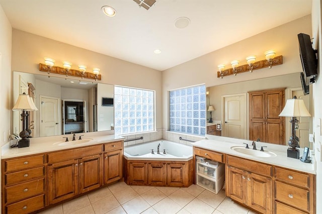 full bathroom featuring a garden tub, two vanities, a sink, and tile patterned floors