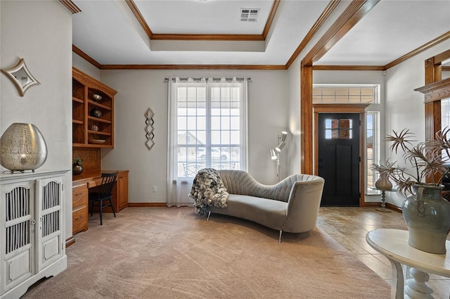 interior space with ornamental molding, light carpet, built in desk, and a tray ceiling