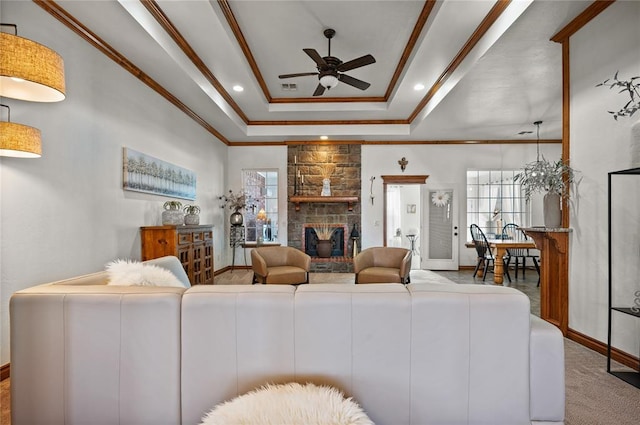 living room with crown molding, a fireplace, a raised ceiling, and carpet