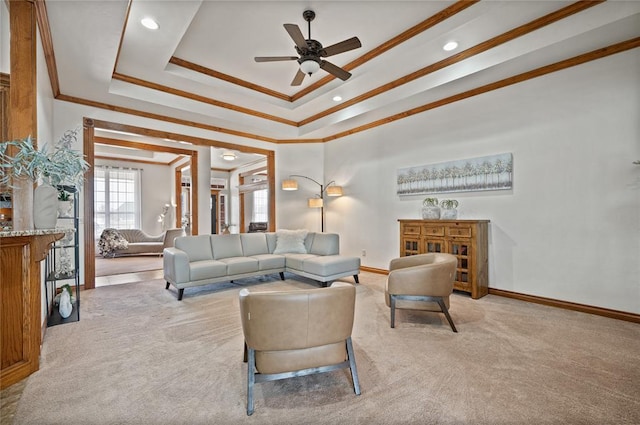 carpeted living room with ornamental molding, a raised ceiling, and ceiling fan