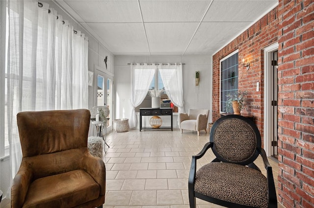 living area featuring light tile patterned flooring and brick wall