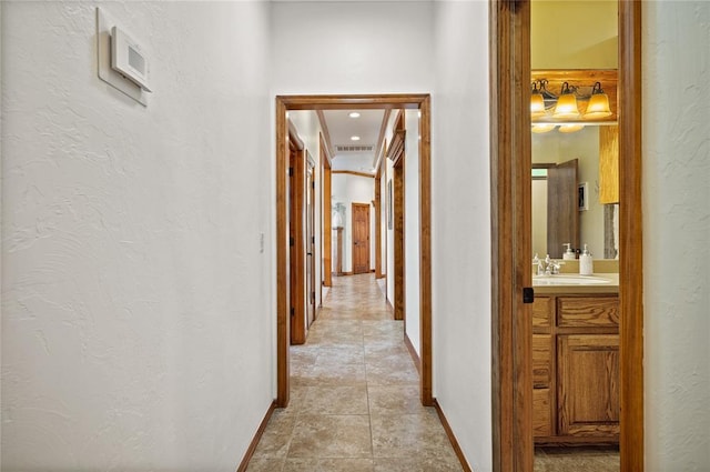 hall featuring sink and light tile patterned floors