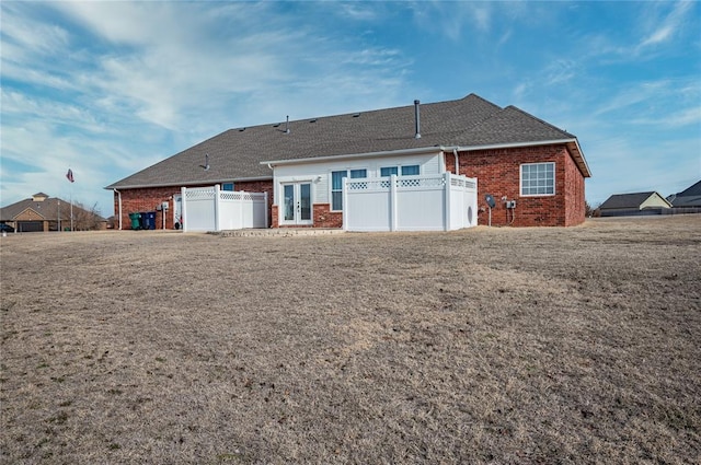 rear view of property with french doors and a lawn