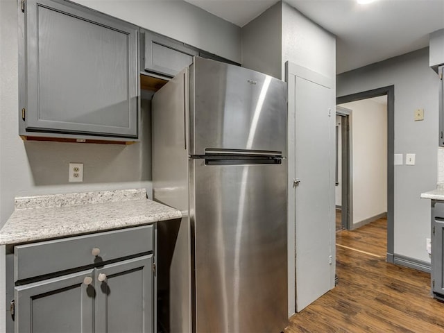 kitchen with dark wood-type flooring, gray cabinets, and stainless steel refrigerator