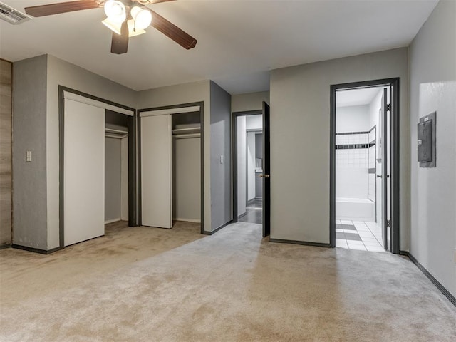 unfurnished bedroom featuring ceiling fan, ensuite bath, and light colored carpet