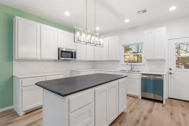 kitchen with sink, white cabinetry, a center island, pendant lighting, and stainless steel appliances