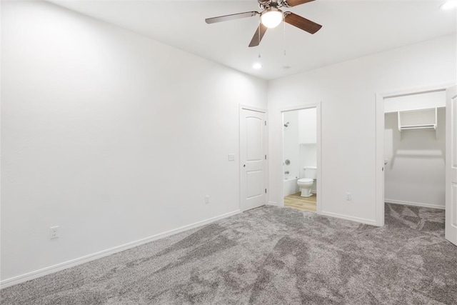 unfurnished bedroom with ensuite bathroom, carpet, a spacious closet, and ceiling fan