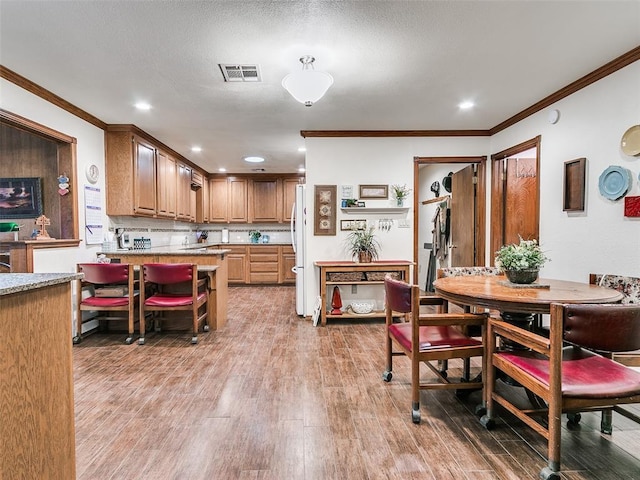 kitchen featuring white refrigerator, ornamental molding, and hardwood / wood-style floors