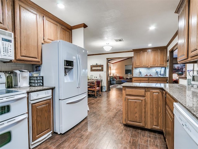 kitchen with white appliances, dark hardwood / wood-style floors, light stone counters, tasteful backsplash, and ornamental molding