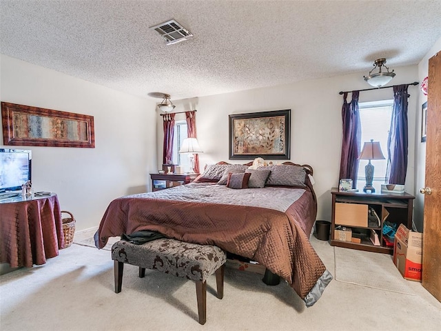 bedroom with light colored carpet and a textured ceiling