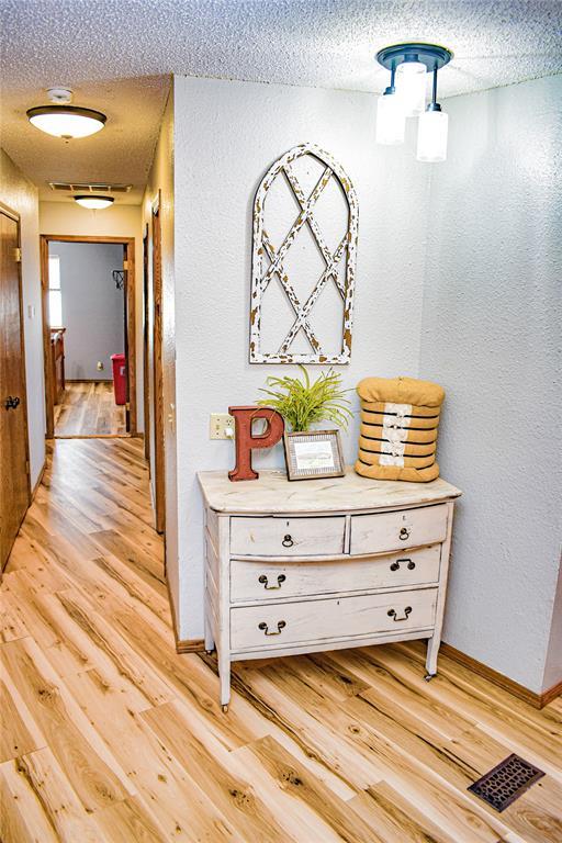 corridor featuring a textured ceiling and light hardwood / wood-style floors