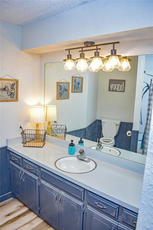 bathroom featuring hardwood / wood-style flooring, vanity, a textured ceiling, and toilet