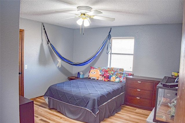 bedroom featuring ceiling fan, a textured ceiling, and light wood-type flooring