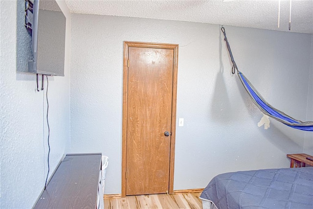 bedroom with a textured ceiling and light wood-type flooring