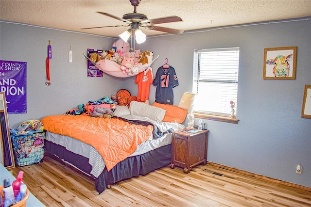 bedroom featuring ceiling fan, a textured ceiling, and light hardwood / wood-style flooring