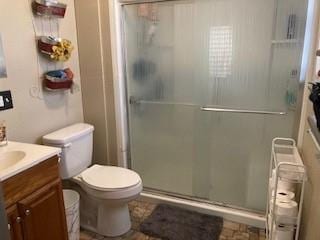 bathroom featuring vanity, toilet, and an enclosed shower