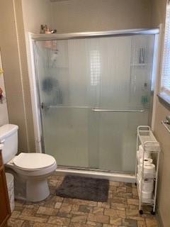 bathroom with vanity, toilet, and a shower with door