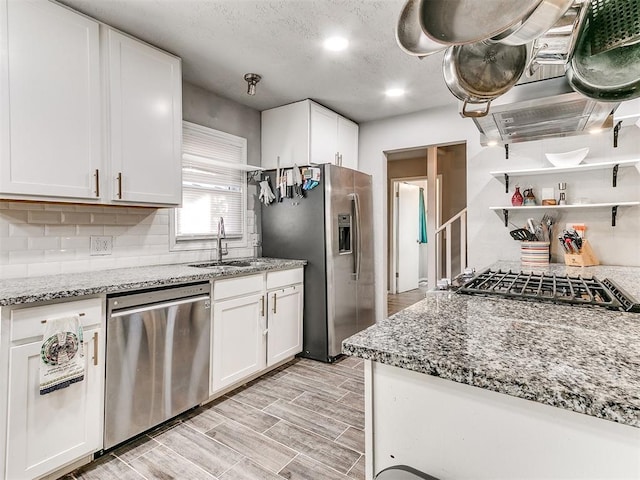 kitchen featuring sink, appliances with stainless steel finishes, light stone counters, tasteful backsplash, and white cabinets