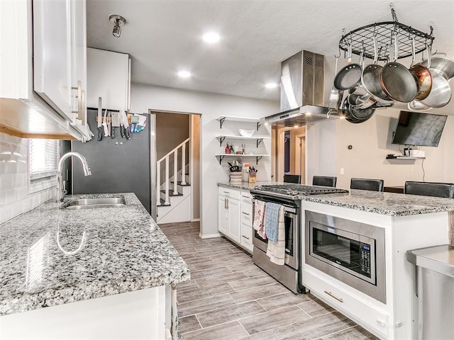 kitchen featuring sink, white cabinetry, backsplash, stainless steel appliances, and island exhaust hood