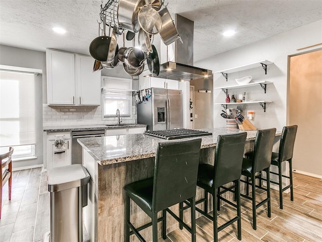 kitchen featuring white cabinetry, appliances with stainless steel finishes, a center island, and light stone counters