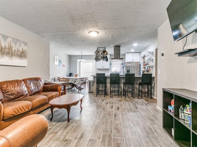 living room featuring sink, a textured ceiling, and a notable chandelier